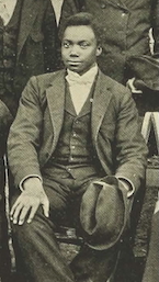 Image of Otho Tobe Johnson dressed in a dark suit sitting for a group photograph.